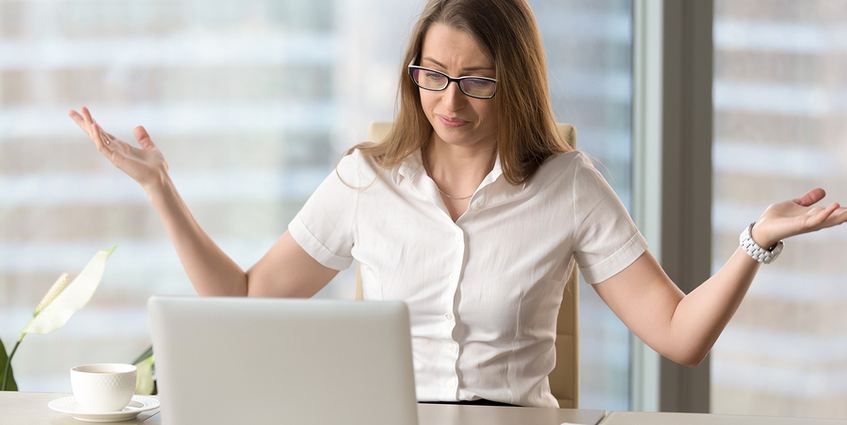 Woman looking at laptop, with arms thrown up in frustration.