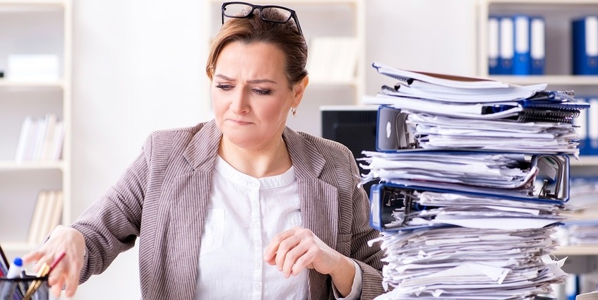 Woman at work with a stack of papers.