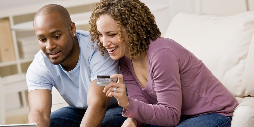 Man and woman shopping on a laptop with a credit card.