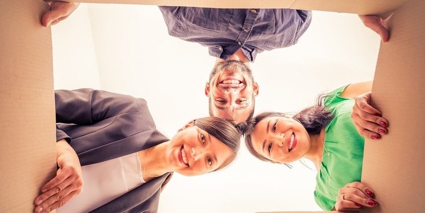 Three people peering down into a cardboard box.